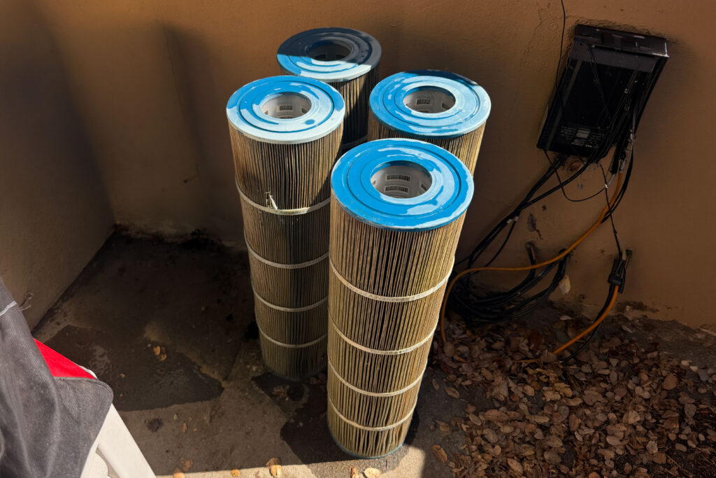 Four pool filter cartridges taht are dirty and green from algae